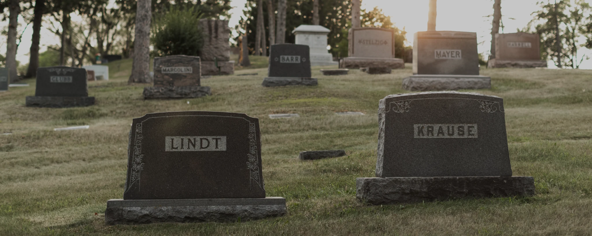 Cemetery With Multiple Headstones And Grave Markers On Grassy Hillside (1)
