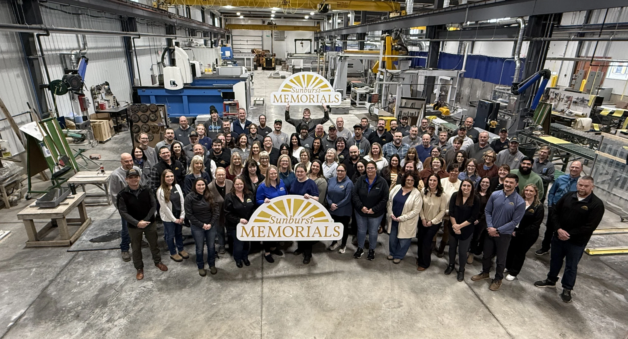 the sunburst memorials team holding company signs with the company name on them
